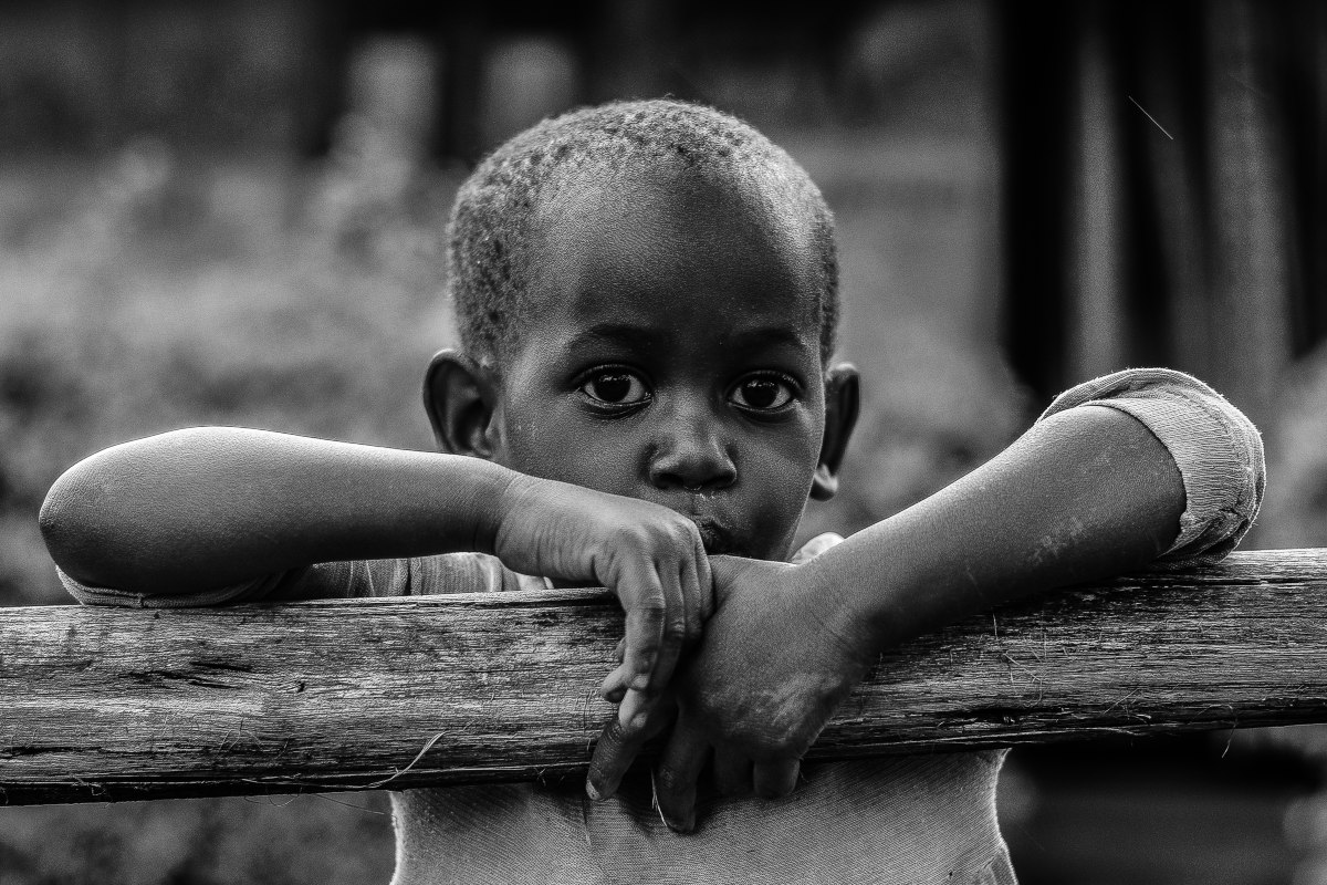 Black-and-white portrait of child on wooden fence